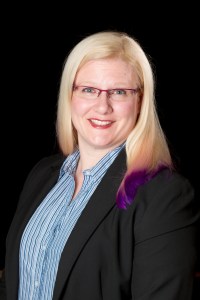 Photo of Crystal in a blue striped shirt and black jacket.