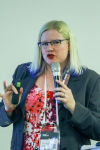 Picture of Crystal in a grey suit and red shirt, holding a microphone.