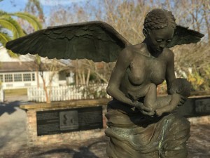 Statue of an angel, face downcast, bare-breasted, holding a baby. This statue of an angel kneels at the center of a commemorative courtyard honoring 2200 infants who were enslaved in the immediate area of the Whitney Plantation and who died before reaching the age of two.